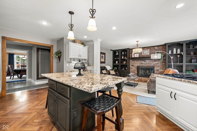 115 Jordan Rd, Indianapolis, IN 46217 - kitchen with white cabinetry, a kitchen breakfast bar, a fireplace, decorative columns, and a kitchen island