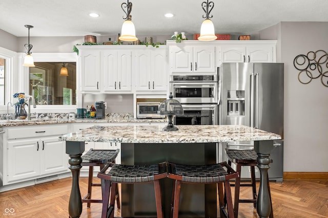 115 Jordan Rd, Indianapolis, IN 46217 - kitchen featuring appliances with stainless steel finishes, a kitchen breakfast bar, white cabinets, a center island, and recessed lighting