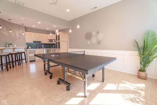 13299 W Wildflower Dr, Columbus, IN 47201 - game room featuring light wood-style flooring, wainscoting, recessed lighting, and a decorative wall