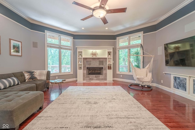 13299 W Wildflower Dr, Columbus, IN 47201 - living area featuring healthy amount of natural light, crown molding, dark wood-style flooring, a tile fireplace, and a ceiling fan