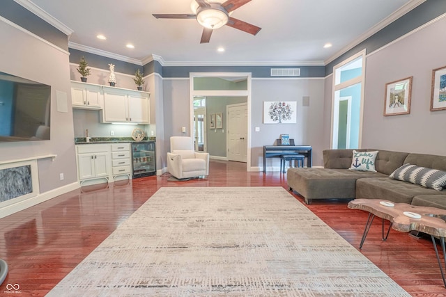 13299 W Wildflower Dr, Columbus, IN 47201 - living room featuring wine cooler, crown molding, bar with sink, a ceiling fan, and dark wood finished floors