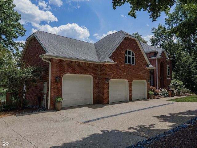 13299 W Wildflower Dr, Columbus, IN 47201 - view of home's exterior featuring roof with shingles, brick siding, concrete driveway, and a garage
