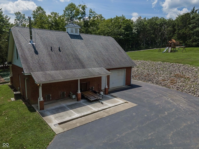 13299 W Wildflower Dr, Columbus, IN 47201 - view of front facade featuring asphalt driveway, brick siding, a front yard, a garage, and roof with shingles