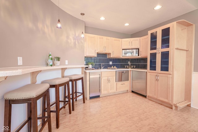 13299 W Wildflower Dr, Columbus, IN 47201 - kitchen with appliances with stainless steel finishes, a breakfast bar area, light wood finished floors, tasteful backsplash, and recessed lighting