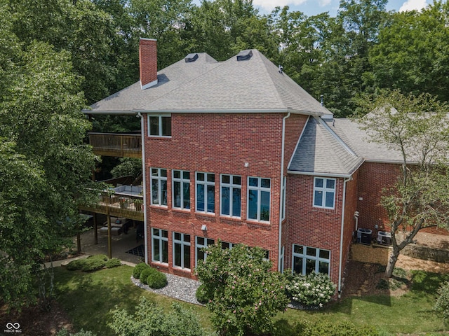 13299 W Wildflower Dr, Columbus, IN 47201 - back of property with a chimney, brick siding, a shingled roof, a balcony, and a lawn