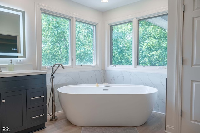 13299 W Wildflower Dr, Columbus, IN 47201 - bathroom featuring vanity, wood finished floors, a freestanding bath, and tile walls
