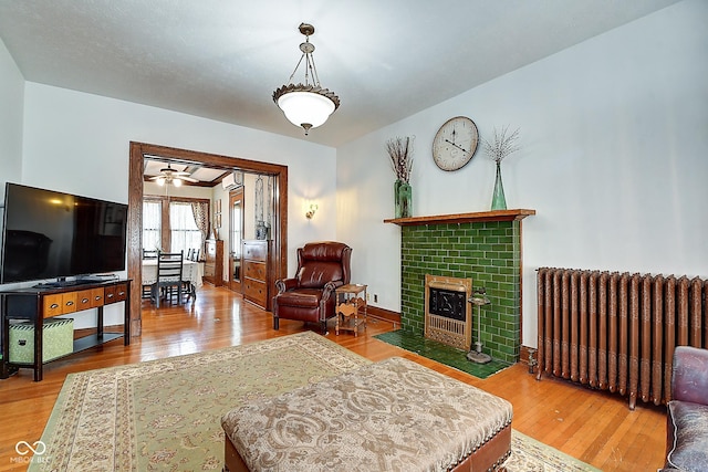1934 N New Jersey St, Indianapolis, IN 46202 - living room with radiator, wood finished floors, a tiled fireplace, and ceiling fan
