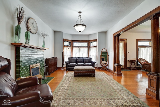 1934 N New Jersey St, Indianapolis, IN 46202 - living area featuring ornate columns, a fireplace, wood finished floors, and a textured ceiling