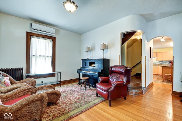 1934 N New Jersey St, Indianapolis, IN 46202 - living area with a wall mounted air conditioner, radiator, arched walkways, and wood-type flooring