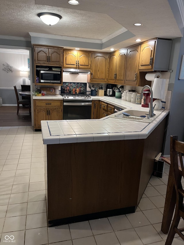 10308 Stormhaven Way, Indianapolis, IN 46256 - kitchen with appliances with stainless steel finishes, crown molding, a textured ceiling, a peninsula, and brown cabinets