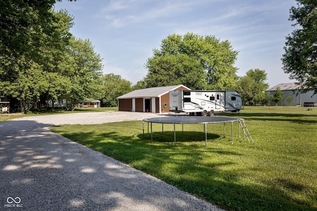 2748 S Meridian Rd, Greenfield, IN 46140 - view of grassy yard featuring a trampoline, an outbuilding, a garage, and gravel driveway