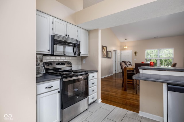 9751 Roxbury Dr, Fishers, IN 46038 - kitchen with stainless steel appliances, dark countertops, white cabinetry, lofted ceiling, and tasteful backsplash