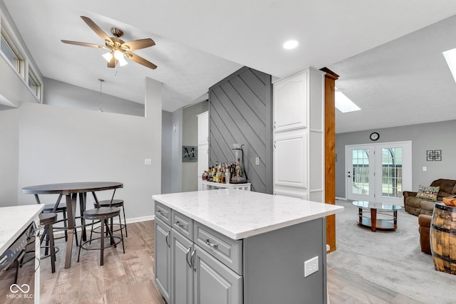 1006 Barry Dr, Lebanon, IN 46052 - kitchen with gray cabinetry, ceiling fan, a skylight, vaulted ceiling, and a kitchen island
