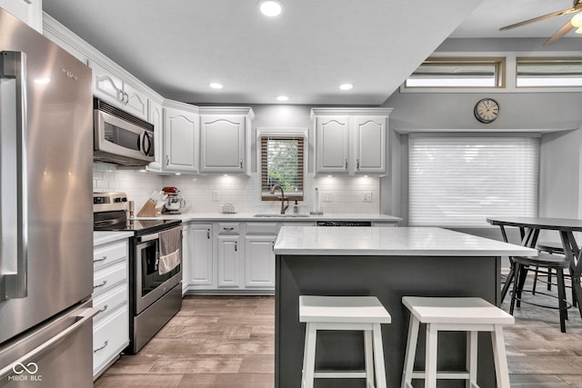 1006 Barry Dr, Lebanon, IN 46052 - kitchen featuring appliances with stainless steel finishes, a kitchen breakfast bar, light countertops, light wood-style floors, and recessed lighting
