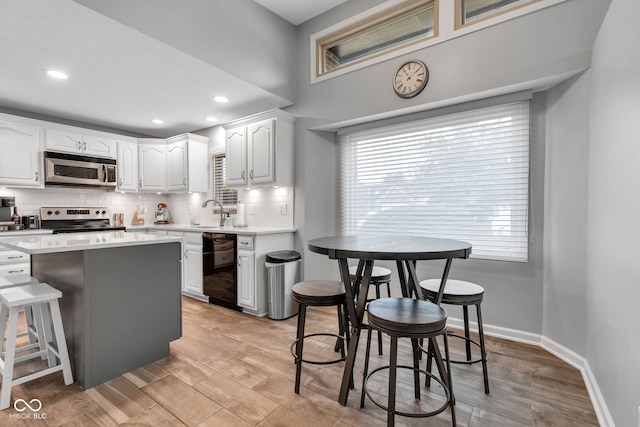1006 Barry Dr, Lebanon, IN 46052 - kitchen featuring appliances with stainless steel finishes, backsplash, white cabinets, light countertops, and light wood-style floors