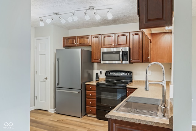 14098 Mimosa Ct, Fishers, IN 46038 - kitchen with stainless steel appliances, light wood-style flooring, light countertops, a textured ceiling, and brown cabinets