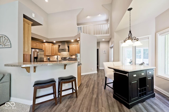 7844 N Timber Run Ct, Indianapolis, IN 46256 - kitchen with stainless steel fridge, wall chimney range hood, a breakfast bar area, tasteful backsplash, and pendant lighting
