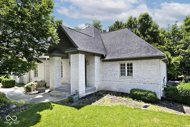 7844 N Timber Run Ct, Indianapolis, IN 46256 - view of front of house with a shingled roof, brick siding, a front lawn, and a patio