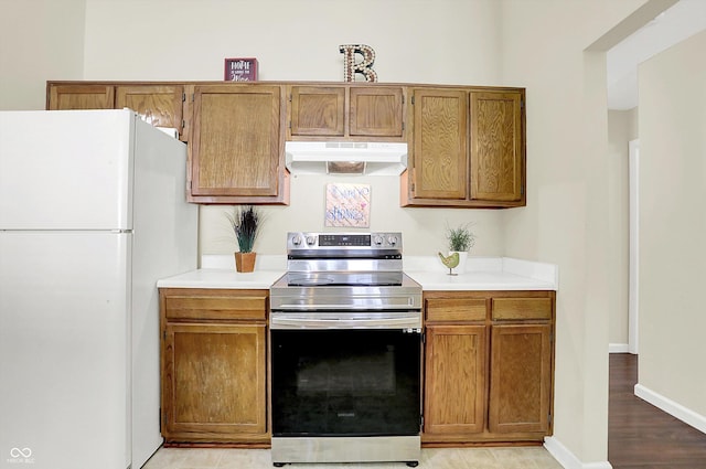 6417 Meadowpond Way, Indianapolis, IN 46235 - kitchen with freestanding refrigerator, under cabinet range hood, stainless steel range with electric stovetop, light countertops, and brown cabinetry