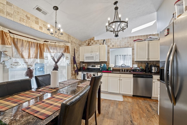6933 Lohr Way, Indianapolis, IN 46214 - kitchen with appliances with stainless steel finishes, a chandelier, vaulted ceiling, dark countertops, and decorative backsplash