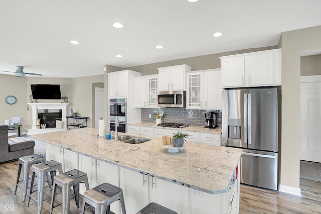 10490 Cleary Trace Dr, Fishers, IN 46040 - kitchen with stainless steel appliances, light wood finished floors, white cabinets, a breakfast bar, and recessed lighting