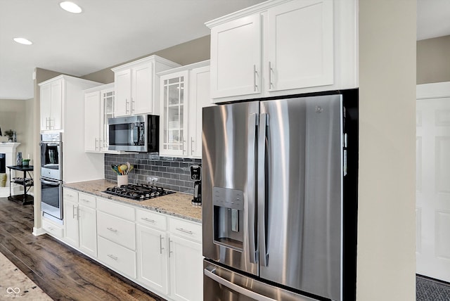 10490 Cleary Trace Dr, Fishers, IN 46040 - kitchen featuring appliances with stainless steel finishes, dark wood finished floors, glass insert cabinets, light stone counters, and white cabinets