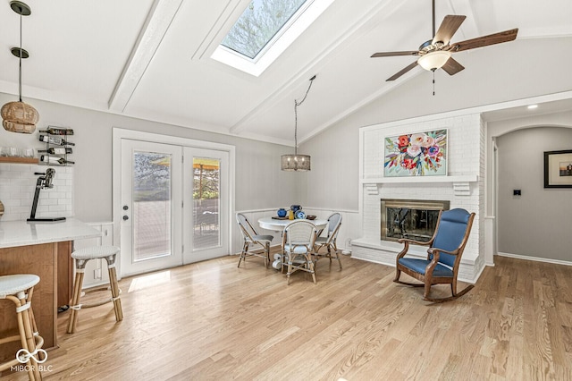 11329 Moss Dr, Carmel, IN 46033 - dining space featuring plenty of natural light, light wood-type flooring, a brick fireplace, a skylight, and a decorative wall
