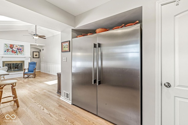 11329 Moss Dr, Carmel, IN 46033 - kitchen with high end refrigerator, ceiling fan, light wood finished floors, and a glass covered fireplace