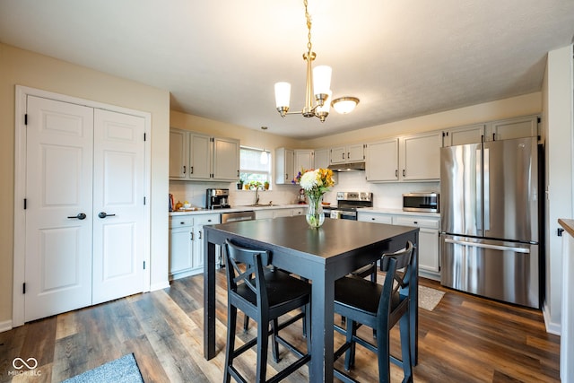 12854 Longleaf Ln, Fishers, IN 46038 - kitchen featuring stainless steel appliances, dark wood-style flooring, a chandelier, light countertops, and decorative light fixtures