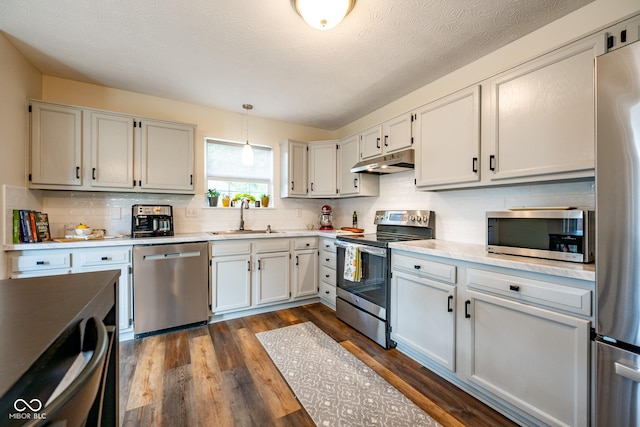 12854 Longleaf Ln, Fishers, IN 46038 - kitchen with appliances with stainless steel finishes, under cabinet range hood, light countertops, dark wood-style flooring, and backsplash