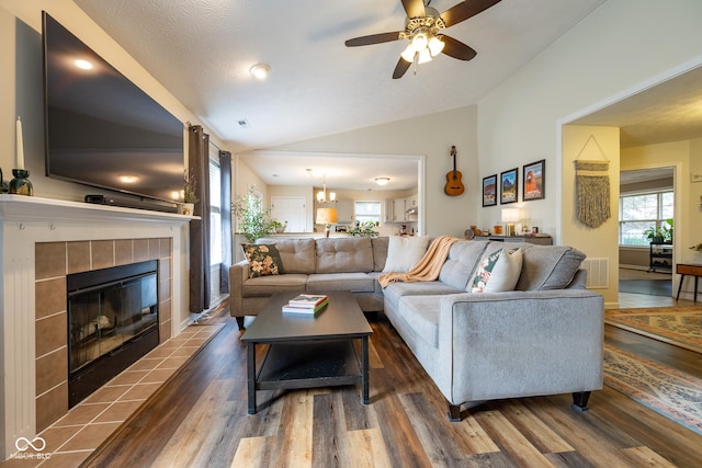 12854 Longleaf Ln, Fishers, IN 46038 - living area featuring vaulted ceiling, wood finished floors, a tiled fireplace, a ceiling fan, and a chandelier
