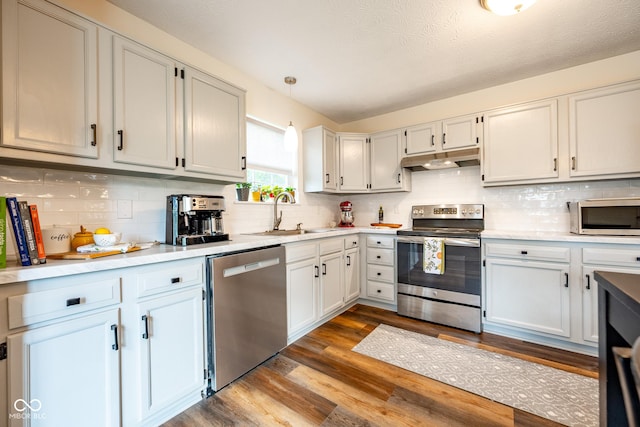 12854 Longleaf Ln, Fishers, IN 46038 - kitchen with appliances with stainless steel finishes, under cabinet range hood, dark wood-style flooring, and decorative backsplash