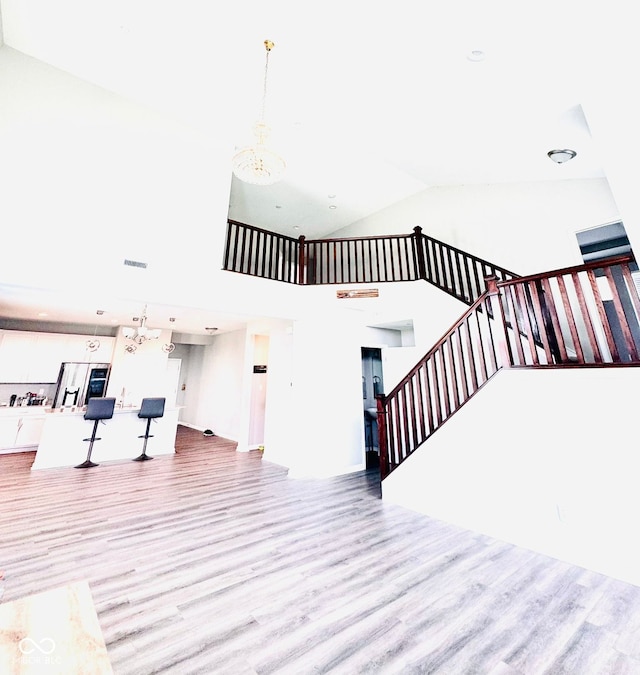 4732 Bethel Creek Blvd, Indianapolis, IN 46239 - unfurnished living room featuring wood finished floors, stairs, a chandelier, and high vaulted ceiling