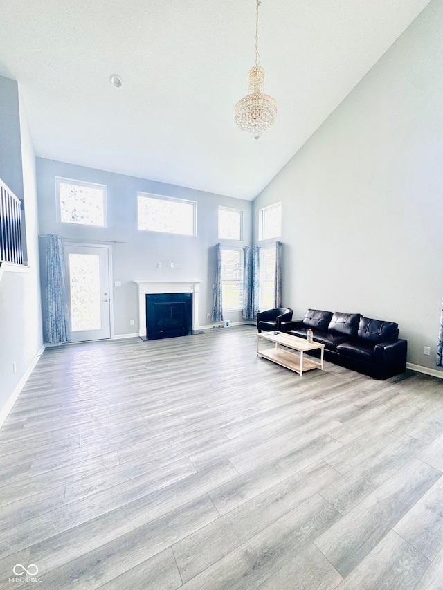 4732 Bethel Creek Blvd, Indianapolis, IN 46239 - living area featuring high vaulted ceiling, light wood finished floors, a fireplace with flush hearth, and a chandelier