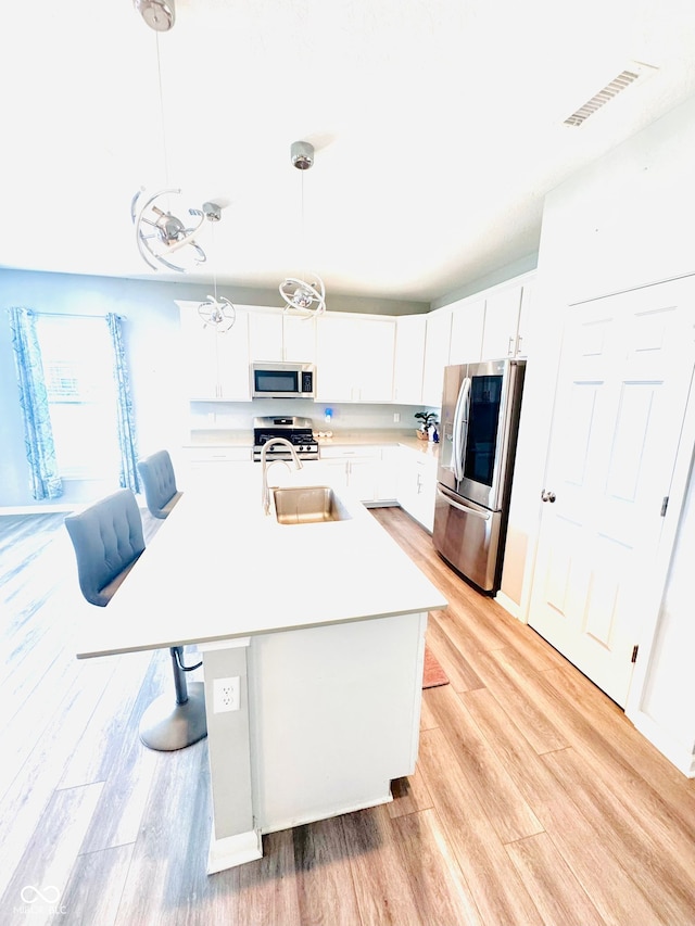 4732 Bethel Creek Blvd, Indianapolis, IN 46239 - kitchen featuring appliances with stainless steel finishes, light countertops, light wood finished floors, a center island with sink, and white cabinets