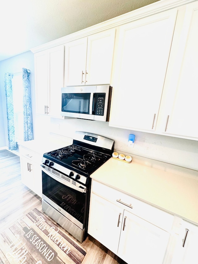 4732 Bethel Creek Blvd, Indianapolis, IN 46239 - kitchen with stainless steel appliances, white cabinets, light wood-style flooring, and light countertops