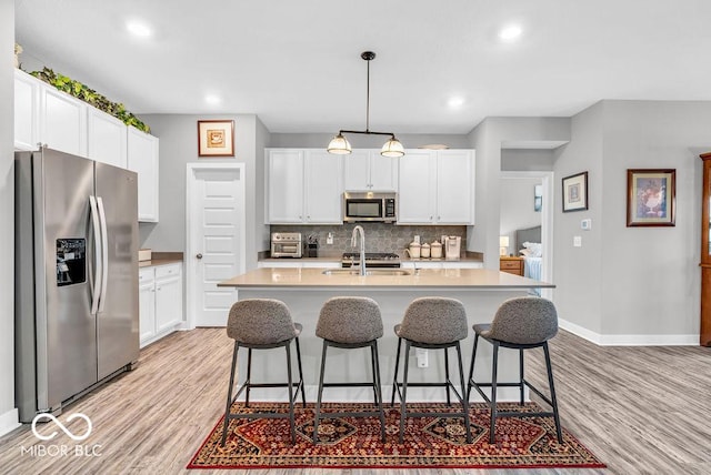9470 Tobin Cir, Avon, IN 46123 - kitchen with stainless steel appliances, light wood finished floors, tasteful backsplash, a kitchen bar, and recessed lighting