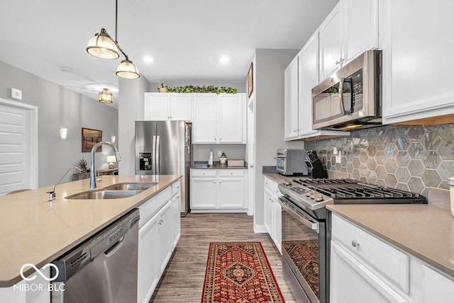 9470 Tobin Cir, Avon, IN 46123 - kitchen featuring appliances with stainless steel finishes, wood finished floors, decorative backsplash, white cabinetry, and hanging light fixtures