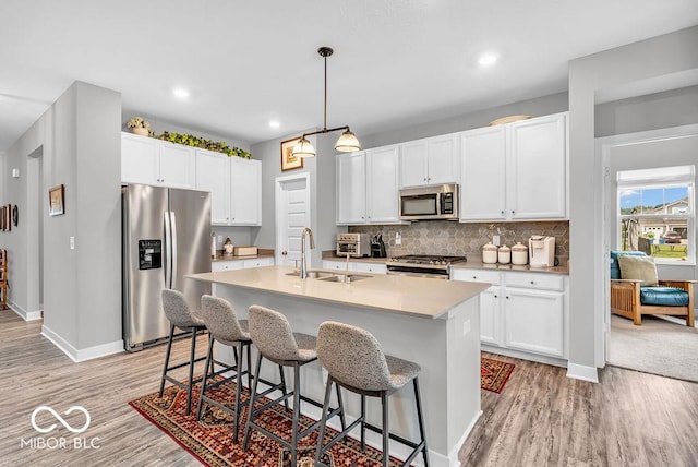 9470 Tobin Cir, Avon, IN 46123 - kitchen with appliances with stainless steel finishes, light wood-style floors, a breakfast bar, a kitchen island with sink, and recessed lighting