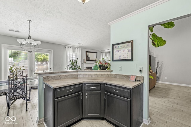 577 Austrian Way, Avon, IN 46123 - kitchen with a peninsula, a chandelier, light wood-style flooring, a textured ceiling, and hanging light fixtures