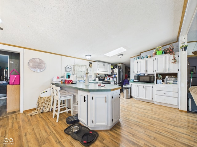 401 S Fletcher St, Frankton, IN 46044 - kitchen with black microwave, freestanding refrigerator, lofted ceiling, a skylight, and a peninsula