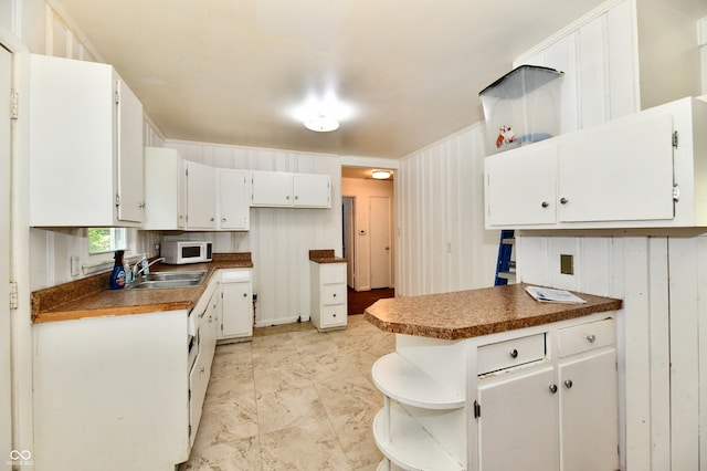8921 E 21st St, Indianapolis, IN 46219 - kitchen featuring open shelves, white microwave, white cabinetry, dark countertops, and a peninsula