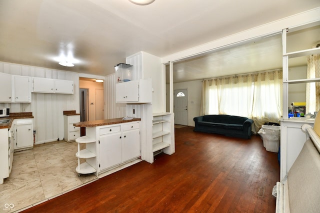 8921 E 21st St, Indianapolis, IN 46219 - kitchen featuring open shelves, white cabinets, a peninsula, white microwave, and wood finished floors