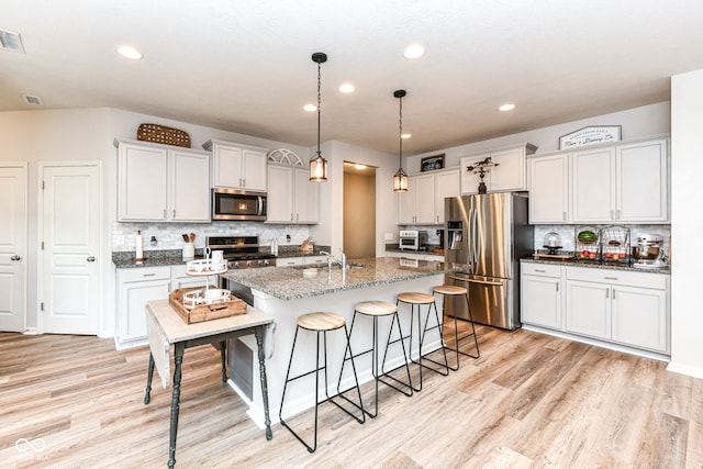 6819 Park Grove Blvd, Whitestown, IN 46075 - kitchen with appliances with stainless steel finishes, a kitchen bar, light wood finished floors, backsplash, and recessed lighting