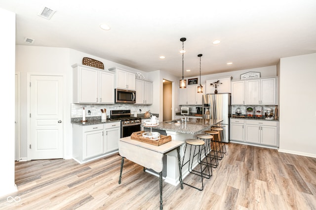 6819 Park Grove Blvd, Whitestown, IN 46075 - kitchen with appliances with stainless steel finishes, light wood-type flooring, a breakfast bar area, backsplash, and an island with sink