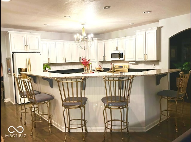 16424 Brookhollow Dr, Noblesville, IN 46062 - kitchen with white microwave, electric range, a chandelier, white cabinets, and stone counters