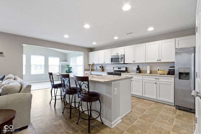 5776 Blue Sky Dr, Whitestown, IN 46075 - kitchen featuring stainless steel appliances, open floor plan, recessed lighting, a kitchen bar, and white cabinetry