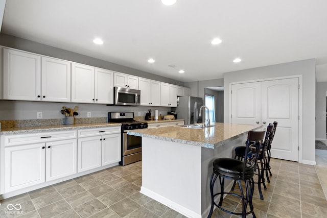 5776 Blue Sky Dr, Whitestown, IN 46075 - kitchen featuring appliances with stainless steel finishes, an island with sink, white cabinets, a breakfast bar, and recessed lighting