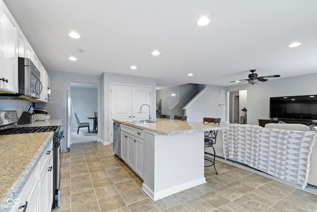 5776 Blue Sky Dr, Whitestown, IN 46075 - kitchen with appliances with stainless steel finishes, a breakfast bar area, a center island with sink, white cabinetry, and recessed lighting