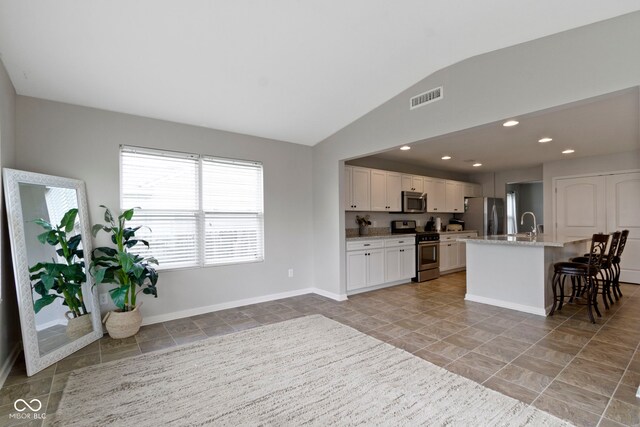 5776 Blue Sky Dr, Whitestown, IN 46075 - kitchen featuring appliances with stainless steel finishes, lofted ceiling, white cabinets, a kitchen breakfast bar, and an island with sink